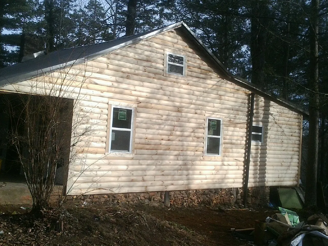 New log siding and dark metal roofing on a gable end in Floral City