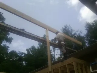 Carpenter setting a ridge beam over a new addition frame — Ice Dam Removal by Roofing Brothers in Floral City