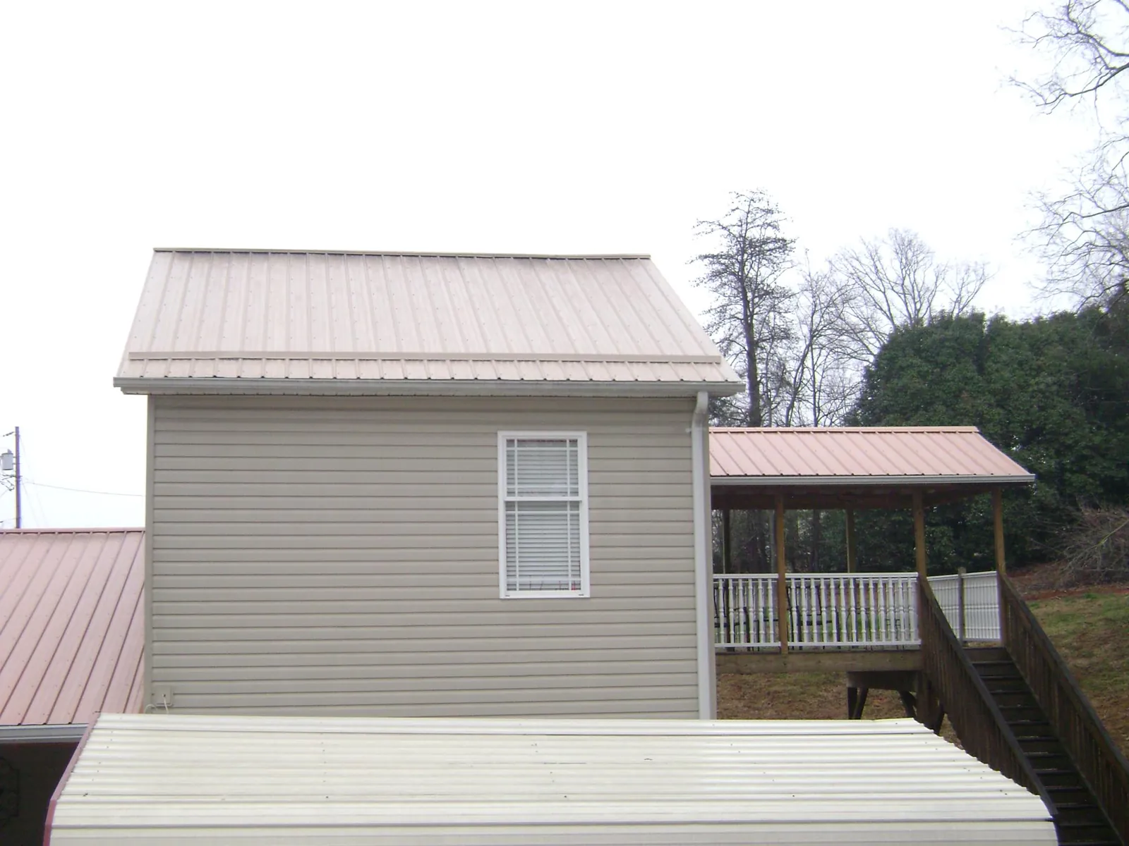 Tan metal roofs on a two story addition and attached porch, from a Roof Replacement job in Floral City